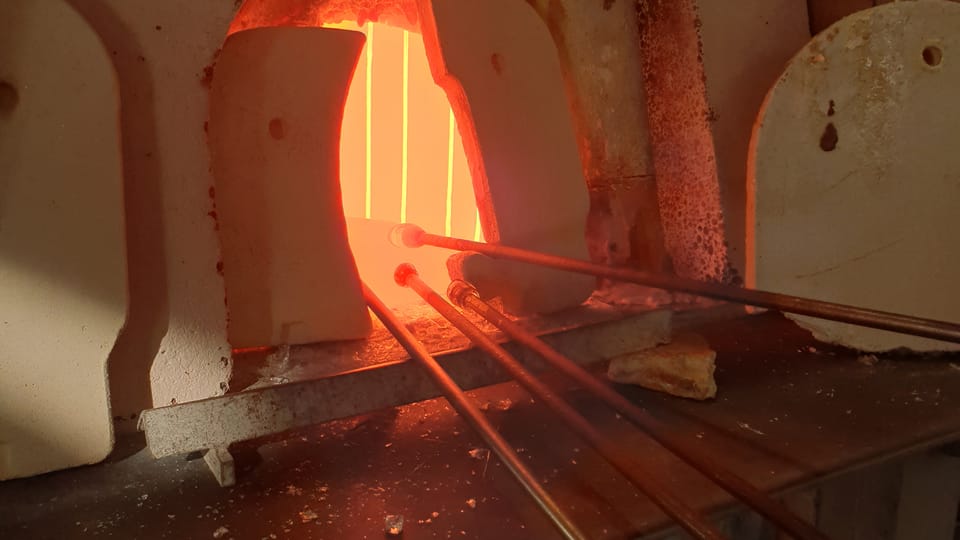 The glassblower gathers the molten glass from the furnace onto a glass blowpipe,  photo: Archive of the Czech Center New York